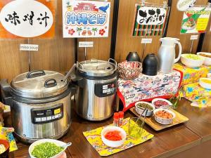 a table with two pots and bowls of food at Green Rich Hotel & Capsule Naha - Artificial hot spring Futamata Yunohana in Naha