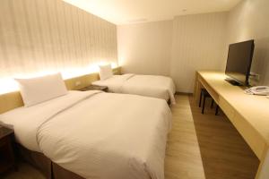 a hotel room with two beds and a flat screen tv at Simple Life Kaohsiung in Kaohsiung