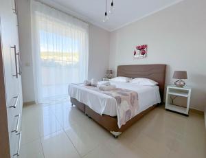 a white bedroom with a large bed and a window at ARIA Luxury Apartments in Nafplio