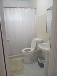 a white bathroom with a toilet and a sink at Mi casa es su casa at Villas de Santamaría in Penonomé