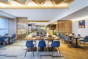 a restaurant with wooden tables and blue chairs at Swiss-Belinn Modern Cikande in Serang