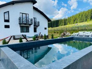 a house with a swimming pool next to a building at Guest House Lileya in Bukovel
