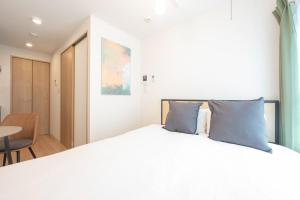 a bedroom with a large white bed with blue pillows at MAT Nogata in Tokyo