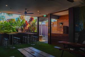 un restaurante con bar con taburetes y mesa en Plantation Hotel Coffs Harbour en Coffs Harbour