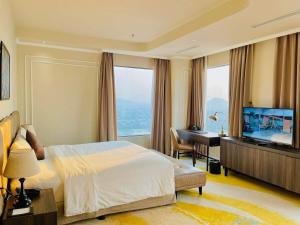 a bedroom with a bed and a desk and a television at La Vela Hue Hotel in Hue
