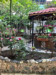 a garden with a gazebo with a bench and flowers at Hotel Livin in Tbilisi City