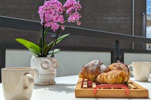 uma mesa com um prato de pão e um vaso com flores em Seconda fila mare by WeHostYou aria condizionata parcheggio em Lido di Fermo