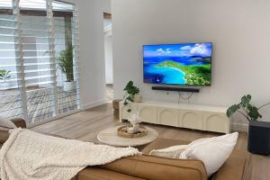 a living room with a couch and a tv on a wall at Casa Tropico - Mission Beach in Mission Beach