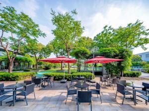 a patio with tables and chairs and red umbrellas at Holiday Inn Shanghai Pudong Kangqiao, an IHG Hotel in Shanghai