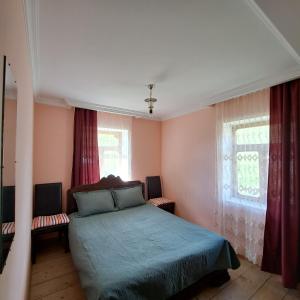 a bedroom with a bed and two windows at Chvibiani Guesthouse & Bar in Ushguli