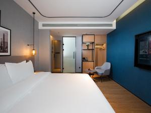a hotel room with a large bed and a chair at Country Inn & Suite by Radisson, Tianjin Wuqing Development Zone Wanda Plaza in Wuqing