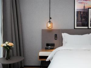 a bedroom with a bed and a vase of flowers at Country Inn & Suite by Radisson, Tianjin Wuqing Development Zone Wanda Plaza in Wuqing
