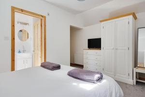 a white bedroom with a bed and a tv at Hilltop Farm in Sturminster Newton
