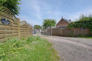 a wooden fence next to a house with a building at Hilltop Farm in Sturminster Newton