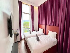 two beds in a hotel room with a window at Capital O 90985 Margo Hotel KK in Kota Kinabalu