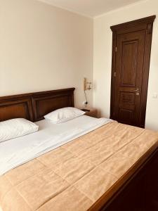een slaapkamer met een groot bed met een houten hoofdeinde bij Едем in Brzezhany