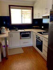cocina con armarios blancos, fregadero y ventana en Kulin Erindale Apartments en Kulin