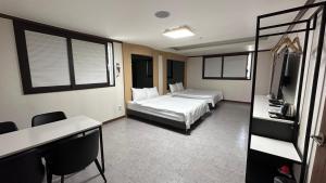 東海市にあるDonghae Gloria Tourist Hotelのベッド2台とデスクが備わるホテルルームです。