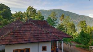 a house with a roof with a mountain in the background at Mountain View Villa Vacation Rental in Idukki +26 photos