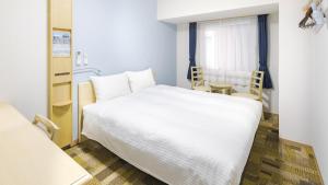 Un dormitorio con una gran cama blanca y una mesa en Toyoko Inn JR Wakayama eki Higashi guchi en Wakayama