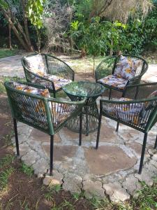 un groupe de trois chaises et une table en verre dans l'établissement Teresita Home, à Nairobi