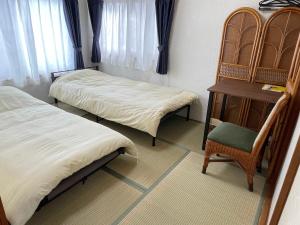 a room with two beds and a table and a chair at Azumi Relax Lodge in Azumino