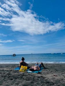 drie mensen zitten op het strand en kijken naar de oceaan bij Putu Guest House Pemuteran in Pemuteran