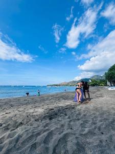 a group of people standing on a beach at Putu Guest House Pemuteran in Pemuteran