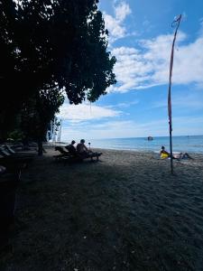 a group of people sitting at a picnic table on the beach at Putu Guest House Pemuteran in Pemuteran