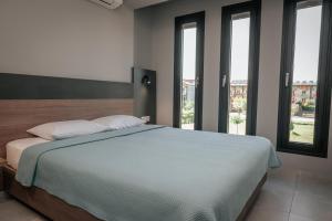 a bedroom with a bed with two pillows and windows at Elizabeth Queen Luxury Rooms in Paralia Katerinis