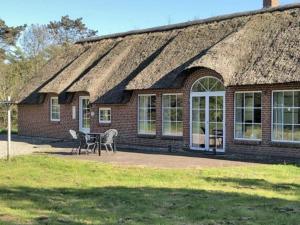 a brick house with a table and chairs in front of it at Luxury Retreat with Pool - By Traum Ferienwohnungen in Ulfborg