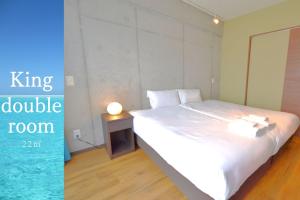 um quarto com uma cama e uma mesa com um candeeiro em Hotel Pescatore Okinawa em Naha
