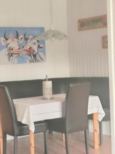 a dining room with a table with chairs and a picture of cows at Gartenhaus in Groß Vollstedt