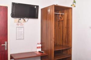 a tv on a wall next to a book shelf at Velodrome Family House Syariah in Ngadipuro