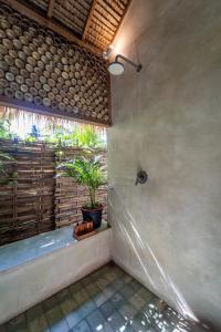 a bathroom with a shower and a potted plant at Villa Mandala in Gili Air