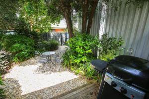 Allambie Cottages - Villa 2 في برايت: حديقة خلفية بها شواية وطاولة وكراسي