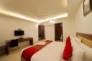 Airport Hotel Peebles في نيودلهي: غرفة نوم بسرير ومكتب وتلفزيون