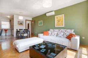Apartment Adagio في زغرب: غرفة معيشة مع أريكة بيضاء وطاولة