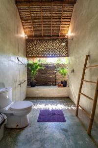 a bathroom with a toilet and a window with plants at Villa Mandala in Gili Air