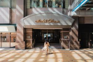 a woman walking in front of a shopping mall at Hotel Okura Fukuoka in Fukuoka
