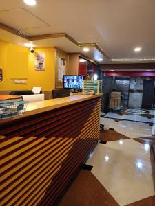 a lobby with a bar with a couch and a television at Orchid Inn SKV3 in Bangkok