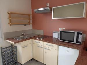 a small kitchen with a sink and a microwave at Studio avec jardin in Bourcefranc