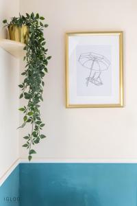 a framed drawing of an umbrella on a wall with a plant at Domus Bat Galim Hotel in Haifa