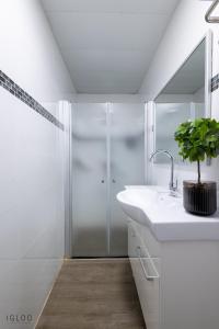 a white bathroom with a sink and a shower at Domus Bat Galim Hotel in Haifa