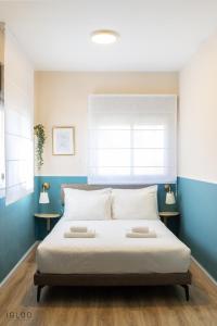 a bedroom with a large white bed with blue walls at Domus Bat Galim Hotel in Haifa