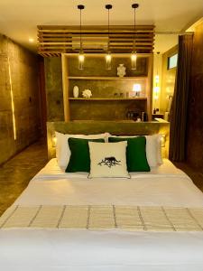 a bedroom with a large bed with green and white pillows at The CIVYT in Ubud