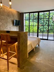 a bedroom with a bed and a desk and windows at The CIVYT in Ubud