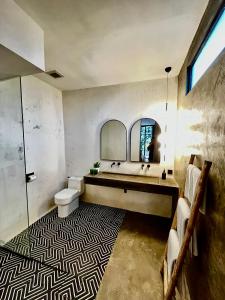 een badkamer met een wastafel, een toilet en een spiegel bij The CIVYT in Ubud