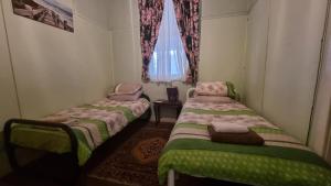 two beds in a small room with a window at Lockhart Railway Hotel in Lockhart