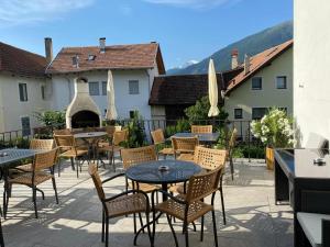 an outdoor patio with tables and chairs and a grill at Garni Sonne in Malles Venosta